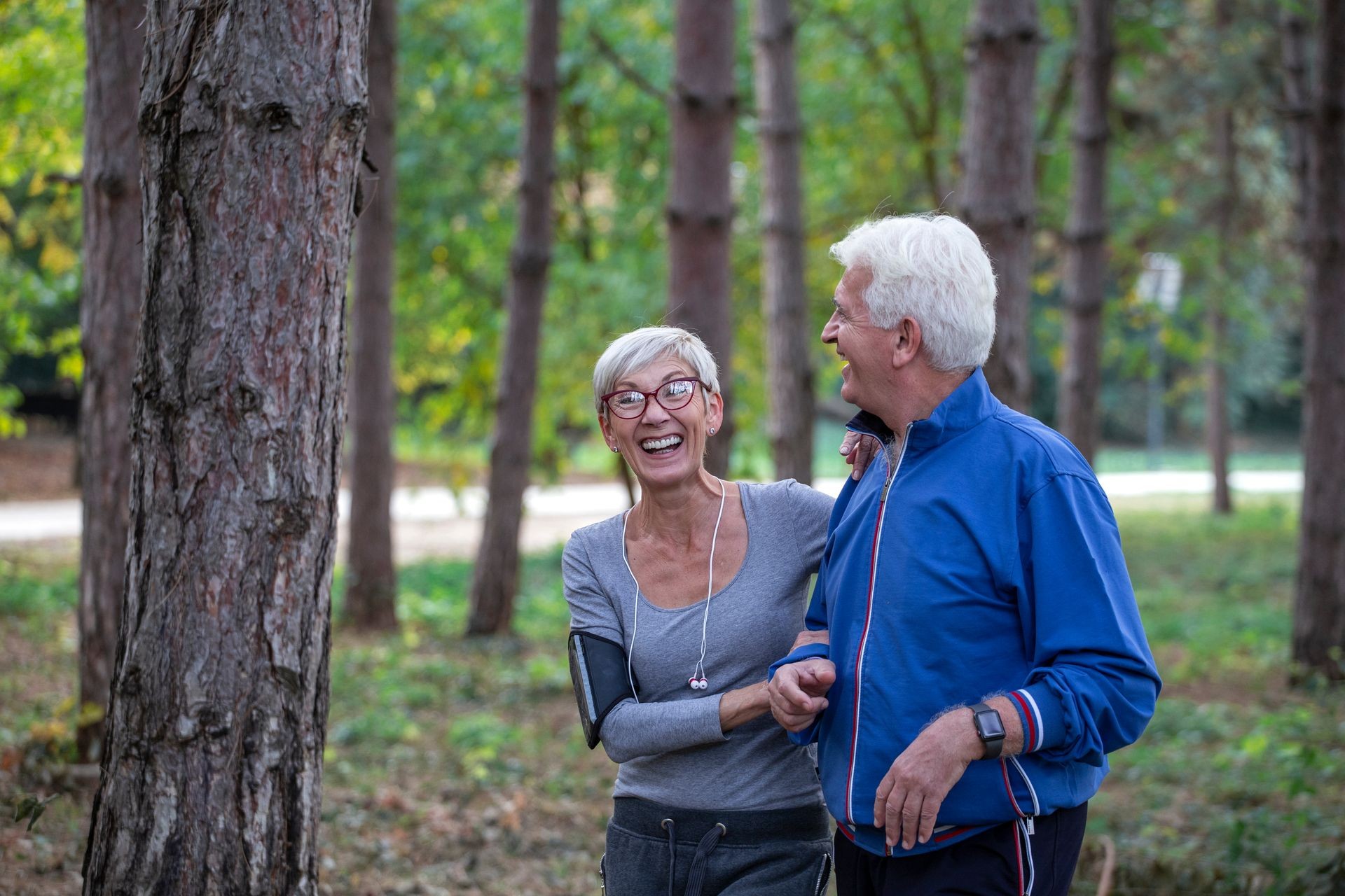 Older couple jogging in the park with distance tracker watch on hands  and smile 