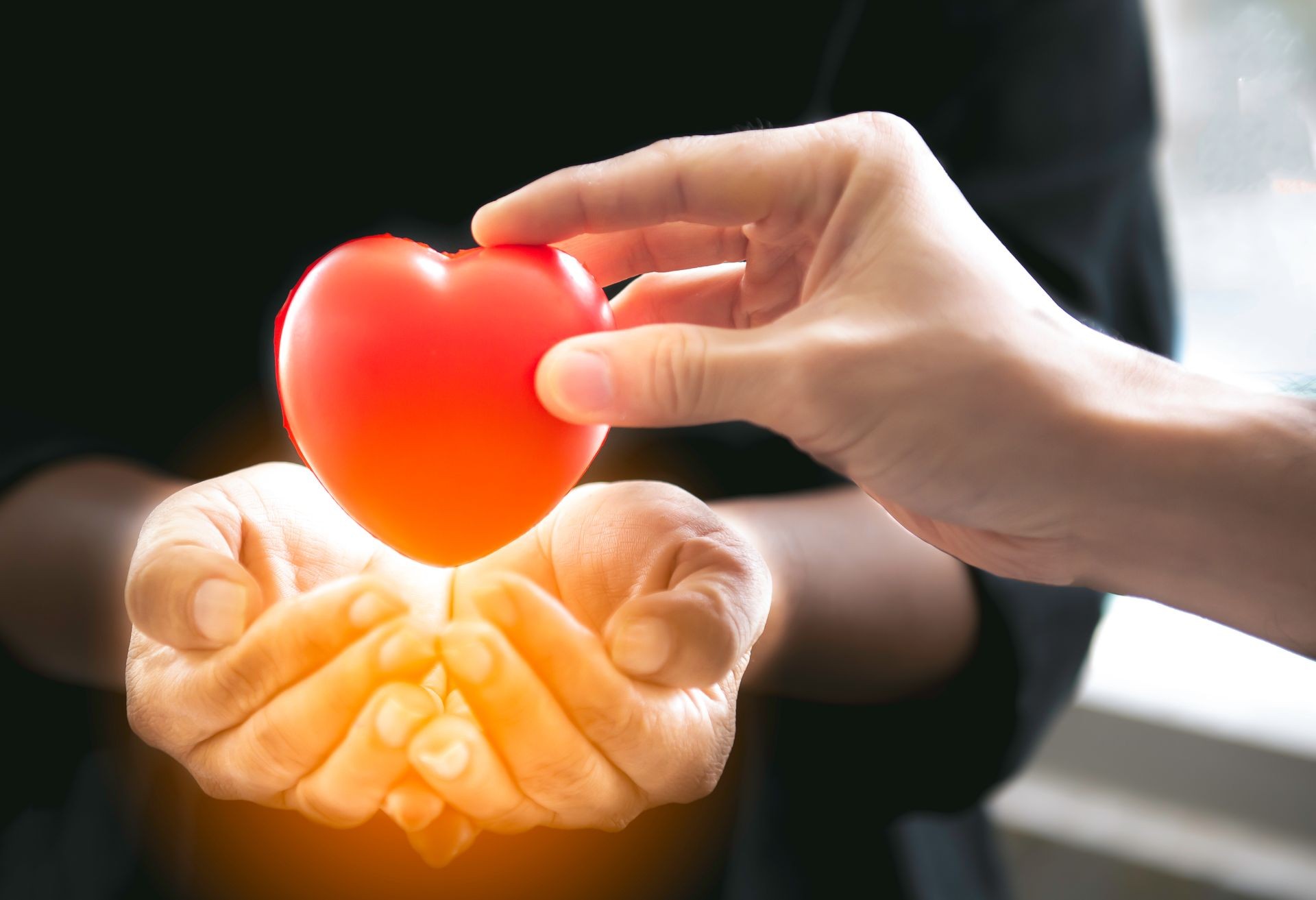 Man giving red rubber heart to palm woman,Male hand give red rubber heart on two hands,Love,family concept,Close up of man and woman hands holding red rubber heart,Give love to the whole world.