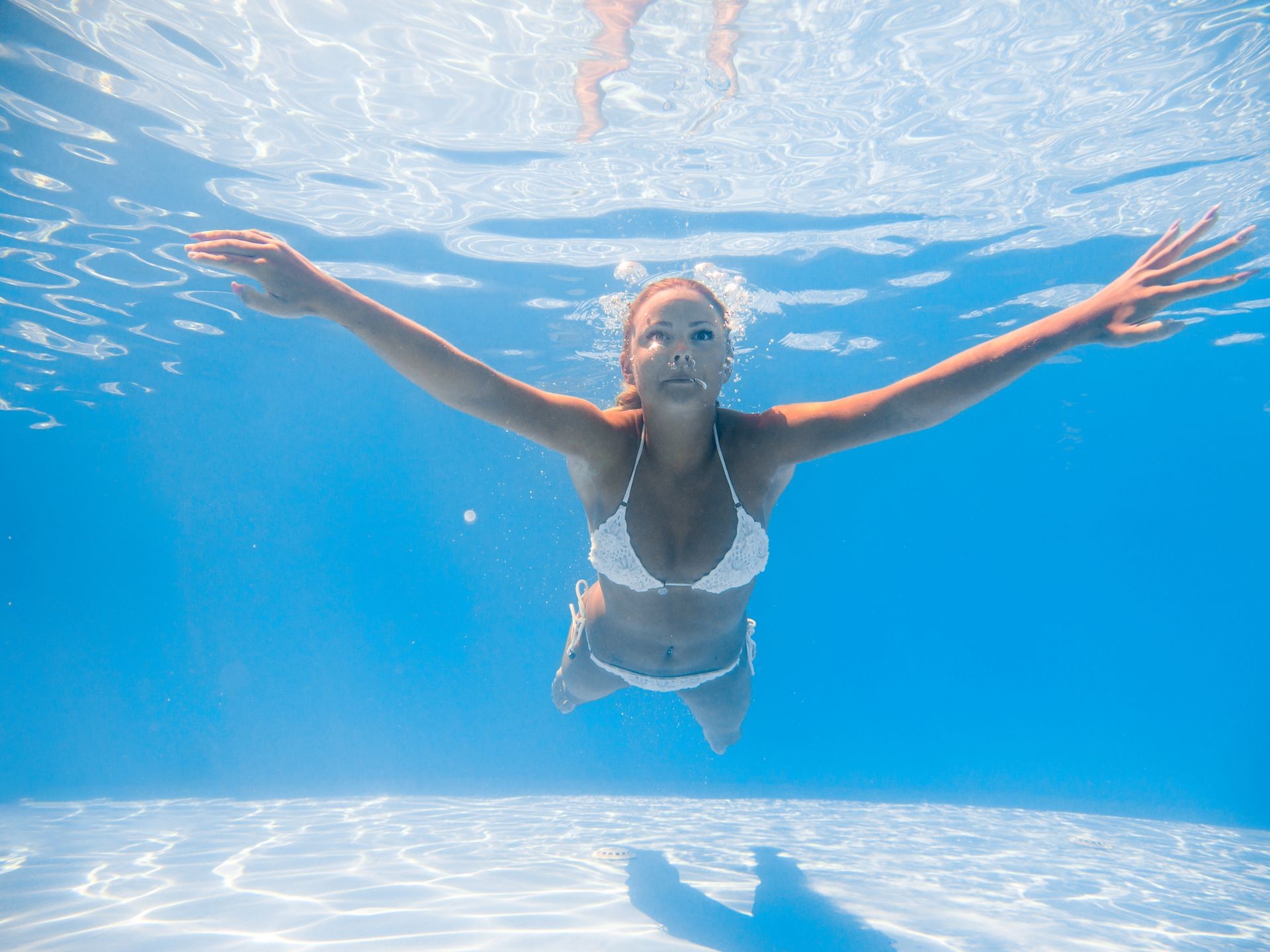 A young blonde woman diving in a blue clean water